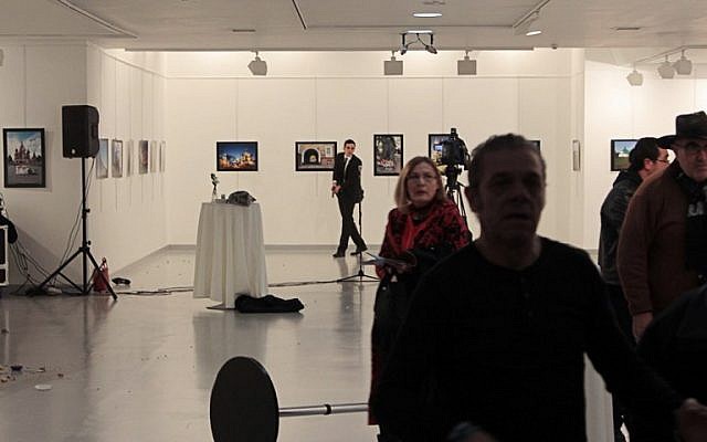 This picture taken on December 19, 2016 in Ankara shows guests leaving a gallery as a gunman holds a weapon, during an attack where Andrey Karlov, the Russian ambassador to Ankara, was shot. (AFP/ Hurryet/Hasim KILIC)
