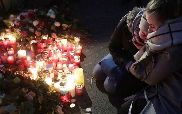 Two women mourn beside candles in Berlin, Germany, Tuesday, Dec. 20, 2016, the day after a truck ran into a crowded Christmas market nearby and killed several people. (AP Photo/Markus Schreiber)