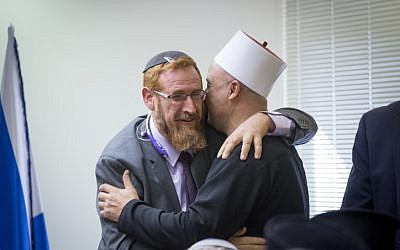 Likud MK Yehudah Glick embraces a Druze religious leader during an emergency meeting over the muezzin law, a bill which intends to ban loudspeakers at mosques, in the Israeli parliament on December 05, 2016. (Miriam Alster/FLASH90)