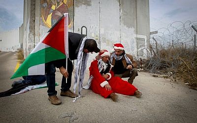 Palestinian protesters dressed as Santa Claus during a demonstration against Israel's  security wall in Bethlehem, on December 23, 2016. (Wisam Hashlamoun/FLASH90)