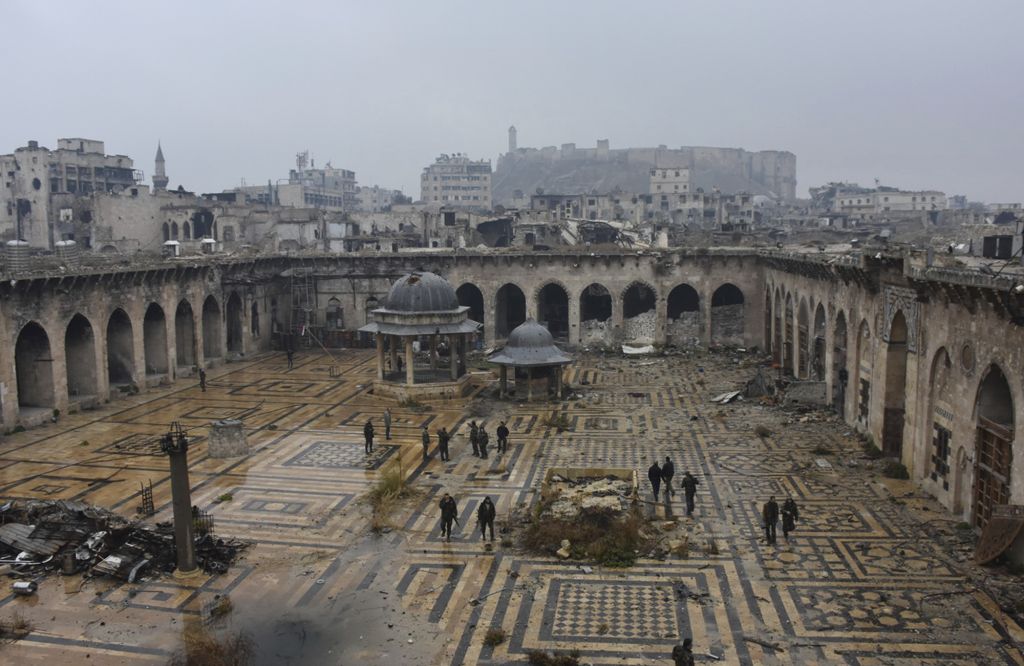 This photo released by the Syrian official news agency SANA, shows Syrian troops and pro-government gunmen marching walk inside the destroyed Grand Umayyad mosque in the old city of Aleppo, Syria, Tuesday, Dec. 13, 2016. (SANA via AP) 