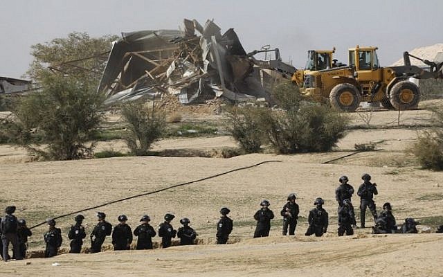 Israeli policemen stand guard as bulldozers demolish homes in the unrecognized Bedouin village of Umm al-Hiran in the Negev desert, on January 18, 2017. (AFP/Menahem Kahana)