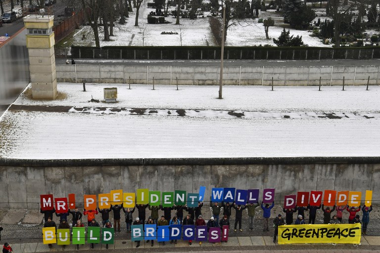 Activists from Greenpeace display a message reading "Mr. President, walls divide. Build Bridges!" along the Berlin wall in Berlin on January 20, 2017 to coincide with the inauguration of Donald Trump as the 45th president of the United States. (AFP PHOTO / John MACDOUGALL)