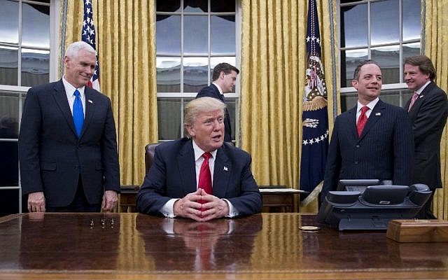 US President Donald Trump, center, speaks to the press at his desk in the Oval Office of the White House  in Washington, DC, January 20, 2017. (AFP PHOTO / JIM WATSON)