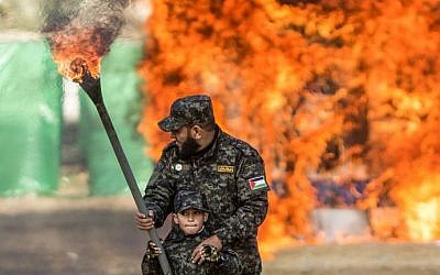 A Palestinian man helps a boy set fire to an Israeli flag during a graduation ceremony for Hamas security forces in Gaza City on January 22, 2017. (AFP PHOTO / MAHMUD HAMS)