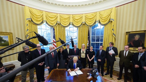 US President Donald Trump signs an executive memorandum on defeating the Islamic State in Iraq and Syria after signing it in the Oval Office of the White House on January 28, 2017, in Washington, DC. (AFP/MANDEL NGAN)