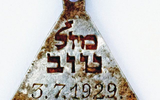 A pendant with the Hebrew words "Mazal Tov" and the date July 3, 1929, found at the site of the Nazi-operated Sobibor death camp. (Yoram Haimi/Israel Antiquities Authority)