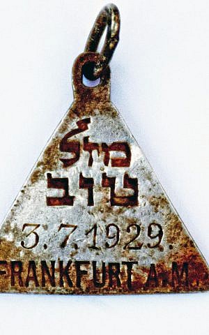 A pendant with the Hebrew words "Mazal Tov" and the date July 3, 1929, found at the site of the Nazi-operated Sobibor death camp. (Yoram Haimi/Israel Antiquities Authority)