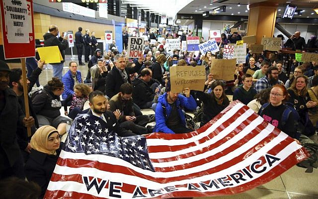 Demonstrators sit down in the concourse and hold a sign that reads "We are America," as more than 1,000 people gather at Seattle-Tacoma International Airport, to protest President Donald Trump's order that restricts immigration to the US, Saturday, January 28, 2017, in Seattle. (Genna Martin/seattlepi.com via AP)