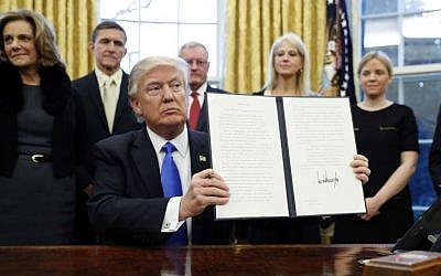 President Donald Trump holds up a signed Executive Order in the Oval Office of the White House, Saturday, Jan. 28, 2017 in Washington. (AP Photo/Alex Brandon) 