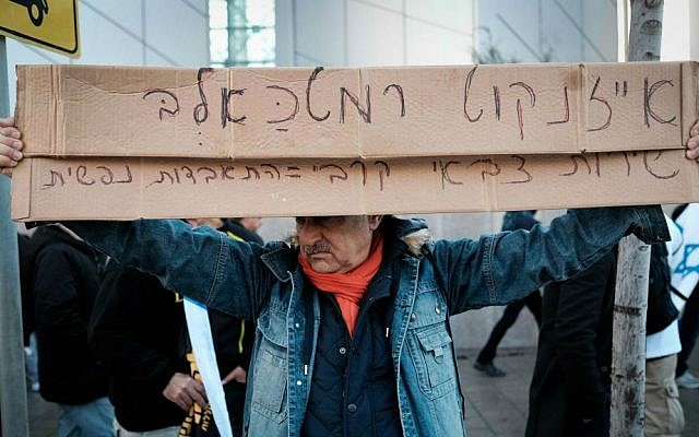 A protester against the verdict in the Azaria trial holds up a sign outside the Kirya military headquarters in Tel Aviv on January 4, 2017, that calls IDF Chief of Staff Lt. Gen. Gadi Eisenkot a 'dog' (Tomer Neuberg/Flash90)