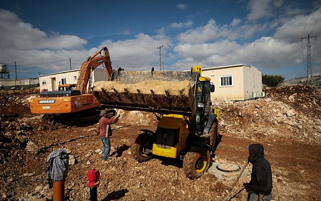 Construction workers work on clearing land for new caravans in the Jewish settlement of Ofra, in the West Bank, on January 29, 2017. (Yaniv Nadav/Flash90)