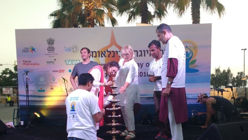 Deputy Chief of Mission at the Embassy of India in Israel, Dr Anju Kumar, in the red scarf, lights a traditional candle at the International Day of Yoga in Tel Aviv on June 21, 2016. (Melanie Lidman/Times of Israel)