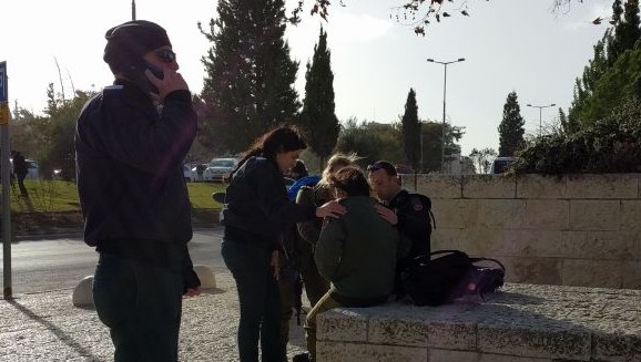 Social workers with the army utilize the "bilateral stimulation" trauma response method to help calm a witness by applying physical pressure on both sides of their body, after the truck ramming attack on January 8, 2017. (Melanie Lidman/Times of Israel)
