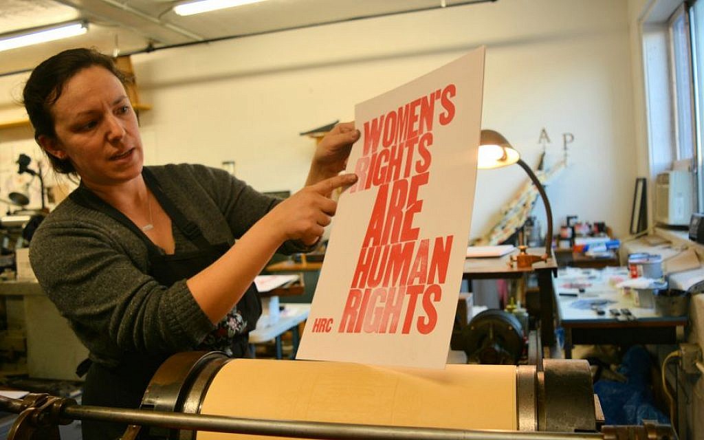 Shelley Barandes examines the poster she is making on an antique letter press for the Women's March on Washington. Barandes, the owner of a design and letterpress print shop in the Boston area, is one of the many American Jews traveling to Washington for the march. (Dina Kraft/Times of Israel)