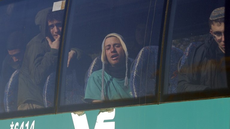 Detained opponents of the evacuation of the illegal Amona outpost on a bus, in which they were placed by police. February 2, 2017. (AFP Photo/Thomas Coex)