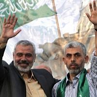 Then-Hamas leader Ismail Haniyeh (L) and newly freed Palestinian security prisoner Yahya Sinwar wave as supporters celebrate the release of 1,027 security prisoners in a swap for kidnapped IDF soldier Gilad Shalit, in Khan Younis, southern Gaza, on October 21, 2011. (AFP/Said Khatib)