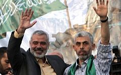 Then-Hamas leader Ismail Haniyeh (L) and newly freed Palestinian security prisoner Yahya Sinwar wave as supporters celebrate the release of hundreds of inmates in a swap for captured IDF soldier Gilad Shalit, in Khan Yunis, southern Gaza on October 21, 2011. (AFP/Said Khatib)