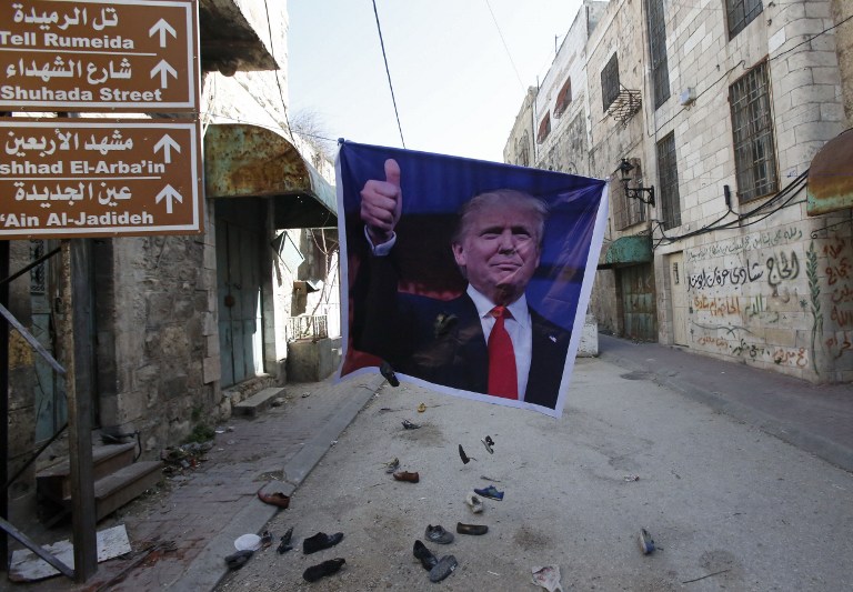 A general view shows old shoes being thrown by Palestinian demonstrator at a poster of US President Donald Trump as they protest against his support of Israel and demand for the Israeli army to re-open Shuhada Street near a Jewish settler enclave in the heart of the flashpoint West Bank city of Hebron, which it has largely closed off to Palestinians on February 24, 2017. (AFP PHOTO / HAZEM BADER)