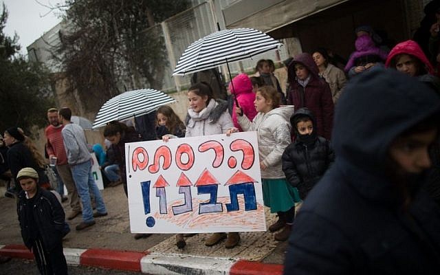 Evicted residents from the Amona outpost protest in front of the Prime Minister's Office in Jerusalem holding a sign that reads "You destroyed, (now) you (must) build", on February 12, 2017. (Yonatan Sindel/Flash90)