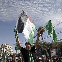 Hamas terrorist Nael Barghouti waves a green Islamic flag and a Palestinian flag to the crowd after arriving in the West Bank city of Ramallah after he was released as part of an exchange for Gilad Shalit, an Israeli soldier held by Hamas, October 18, 2011. (AP/Majdi Mohammed)