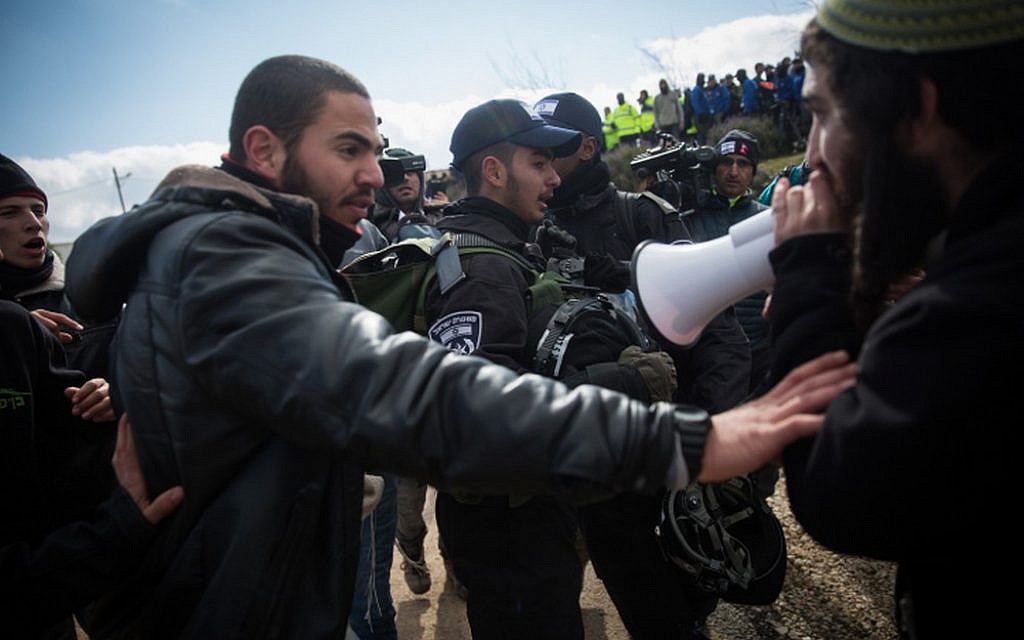 A resident of the Amona outpost shouts at police officers through a megaphone during the evacuation of the illegal settlement on February 1, 2017. (Hadas Parush/Flash90)