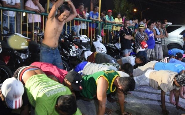 This photo taken March 9, 2017 shows detained drunks and shirtless men, doing 60 push-ups, as punishment during the police's operation called "Oplan RODY", an acronym for Rid the Streets of Drinkers and Youths, and also President Rodrigo Duterte's nickname, at Paranaque police headquarters, suburban Manila. AFP PHOTO / TED ALJIBE)
