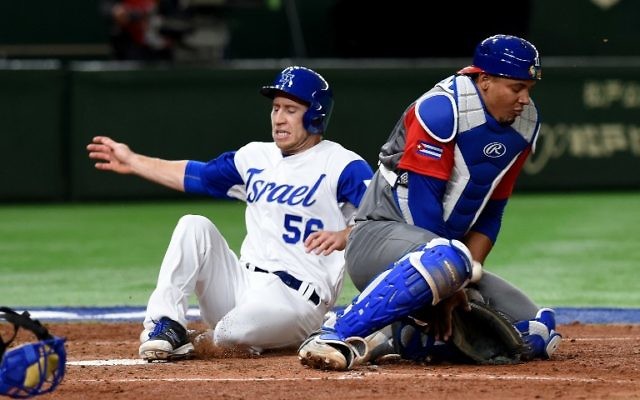 Israeli third baseman Ty Kelly (L) arrives at the home plate next to Cuban catcher Yosvani Alarcon after a single hit by right fielder Zach Borenstein at the top of the sixth inning during the World Baseball Classic Pool E second round match between Cuba and Israel at Tokyo Dome in Tokyo on March 12, 2017 (AFP /TORU YAMANAKA)