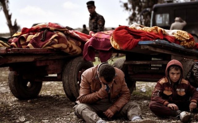 Relatives mourn as bodies of Iraqi residents of west Mosul killed in an airstrike targeting Islamic State jihadists are placed on carts and covered with blankets, March 17, 2017. (AFP/Aris Messinis)
