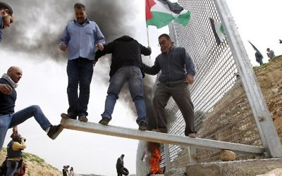 Palestinian demonstrators attempt to damage an iron fence, setup by Israeli security forces, between the Palestinian village of Beit Jala and the Jerusalem area, on March 30, 2017 during Land Day protest in the Israeli occupied West Bank. (AFP PHOTO / Musa AL SHAER)