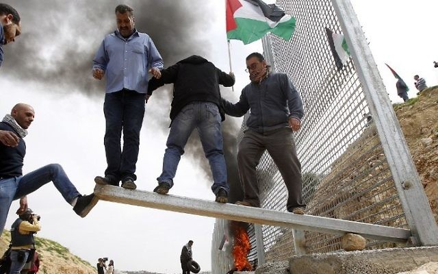 Illustrative: Palestinian demonstrators attempt to damage an iron fence, setup by Israeli security forces, between the Palestinian village of Beit Jala and the Jerusalem area, on March 30, 2017 during Land Day protest in the Israeli occupied West Bank. (AFP PHOTO / Musa AL SHAER)