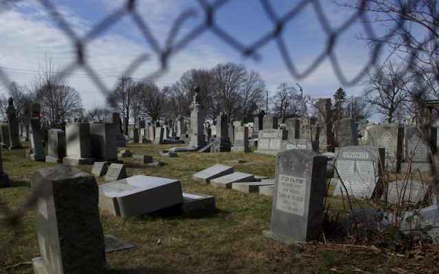 Vandalized Jewish tombstones are framed through a hole in the fence surrounding Mount Carmel Cemetery February 27, 2017 in Philadelphia, Pennsylvania. (Mark Makela/Getty Images/AFP)