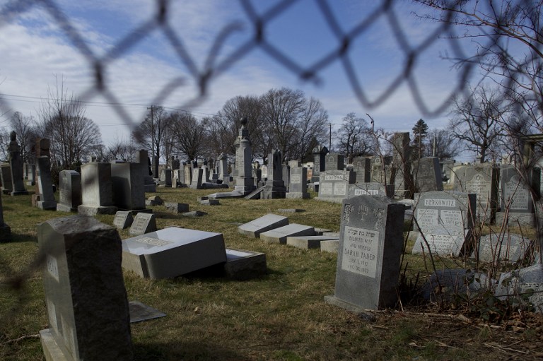 Vandalized Jewish tombstones are framed through a hole in the fence surrounding Mount Carmel Cemetery February 27, 2017 in Philadelphia, Pennsylvania. (Mark Makela/Getty Images/AFP)