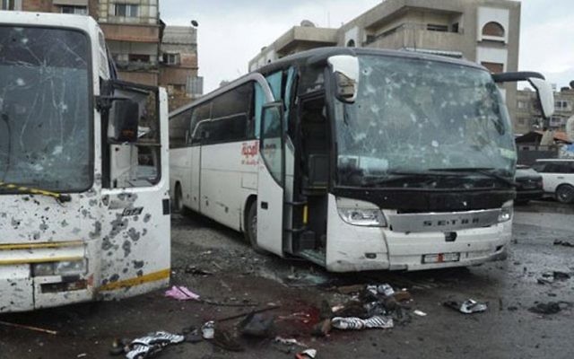 This photo released by the Syrian official news agency SANA shows blood soaked streets and several damaged buses in a parking lot at the site of an attack by twin explosions in Damascus, Syria, Saturday, March 11, 2017. (SANA via AP)