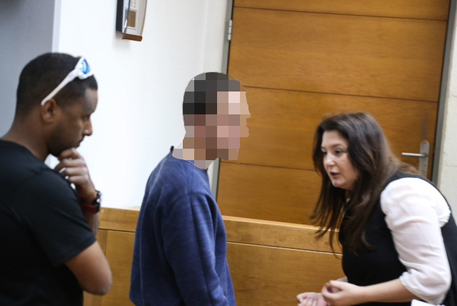 A Jewish Israeli teen is brought for a court hearing at the Rishon Lezion Magistrate's Court, on suspicion of issuing fake bomb threats against Jewish institutions in the US and around the world, on March 23, 2017. At right is his lawyer, Galit Besh (Flash90)