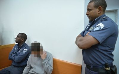 An Israeli teen, center, suspected of calling in bomb threats to hundreds of institutions is brought to the Rishon Lezion Magistrate's Court on March 30, 2017. (Flash90) 