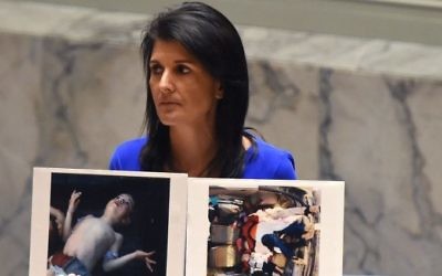 US Ambassador to the UN Nikki Haley holds photos of victims as she speaks at the UN Security Council in an emergency session on April 5, 2017 about the suspected deadly chemical attack that killed civilians, including children, in Syria. (AFP/Timothy A. Clary)