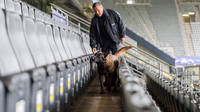 A policeman and an explosive detection sniffer dog do their work at the stadium in Dortmund, western Germany, on April 12, 2017 prior to the UEFA Champions League quarter-final, first-leg football match of German first division Bundesliga club Borussia Dortmund vs Monaco. (AFP PHOTO / DPA / Guido Kirchner)