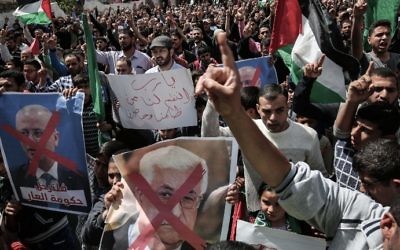 Gaza supporters of the Hamas terror group hold crossed-out portraits of PA President Mahmoud Abbas (C) and PM Rami Hamdallah during a protest on April 14, 2017, in Khan Yunis. (AFP Photo/Said Khatib)