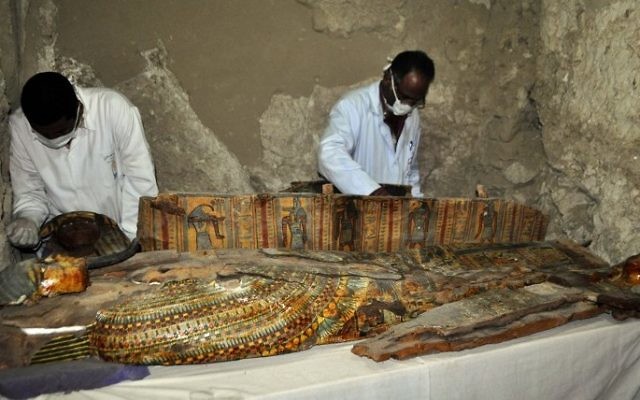 Egyptian archaeologists work on a wooden coffin discovered in a 3,500-year-old tomb in the Draa Abul Nagaa necropolis, near the southern Egyptian city of Luxor, April 18, 2017. (AFP/Stringer)