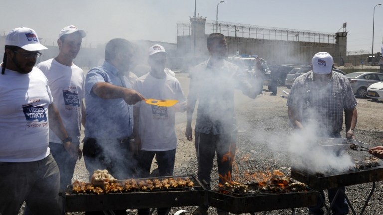 Israeli right-wing activists barbecue outside Ofer Prison in the West Bank village of Betunia on April 20, 2017. (AFP Photo/Menahem Kahana)