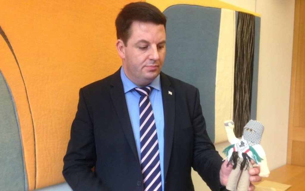 British MP Andrew Percy holds a terror doll teaching aid used in Palestinian schools. (Jenni Frazer/ Times of Israel)