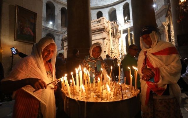Christian pilgrims light candles inside the Holy Sepulchre church during Good Friday in Jerusalem Friday, April 14, 2017. (Dan Balilty/AP)
