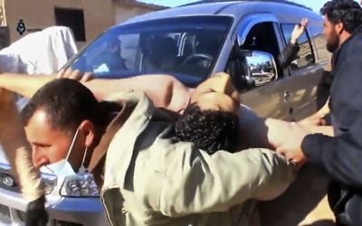 This frame grab from video provided on Tuesday April 4, 2017, by Qasioun News Agency, shows a Syrian man carrying a man on his back who has suffered from a suspected chemical attack, in the town of Khan Sheikhoun, northern Idlib province, Syria (Qasioun News Agency, via AP)