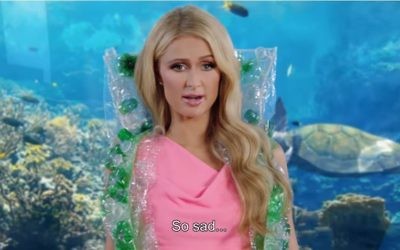 Paris Hilton sports a cape made of plastic bottles that allegedly came from the stomachs of sea turtles in a mock ad released by SodaStream on March 29, 2017. (Screen capture/YouTube)