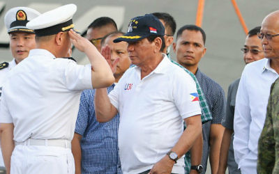 Philippine President Rodrigo Duterte (C) returns a salute from a Chinese naval officer (L) as Philippine Defense Secretary Delfin Lorenzana (R) looks on during Duterte's arrival to visit the guided missile frigate Changchun berthed at the Davao international port on May 1, 2017. (MANMAN DEJETO / AFP)