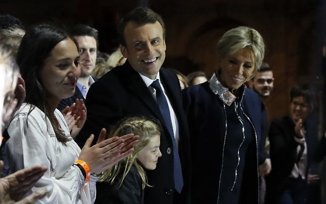 French president-elect Emmanuel Macron (C) and his wife Brigitte Trogneux (R) greet supporters in front of the Pyramid at the Louvre Museum in Paris on May 7, 2017, after the second round of the French presidential election. (AFP PHOTO / POOL / Thomas SAMSON)