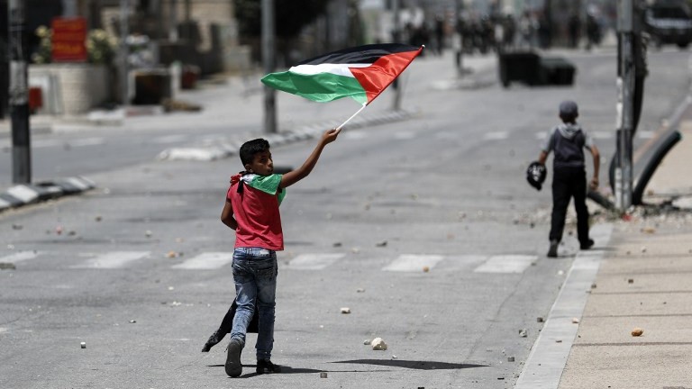 A Palestinian boy waves a Palestinian flag during 'Nakba' Day clashes with Israeli security forces in the West Bank city of Bethlehem on May 15, 2017. (AFP Photo/Thomas Coex)