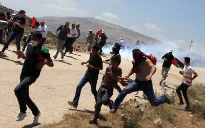 Palestinian demonstrators run for cover during clashes with Israeli forces during a protest in the West Bank village of Bait Djan, near the city of Nablus, on May 19, 2017. (AFP PHOTO / JAAFAR ASHTIYEH)