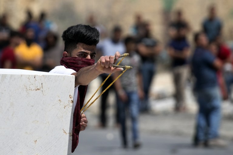 A Palestinian youth uses a slingshot against Israeli security forces during a violent protest in solidarity with Palestinian security prisoners outside Nablus on May 26, 2017. (Jaafar Ashtiyeh/AFP PHOTO)